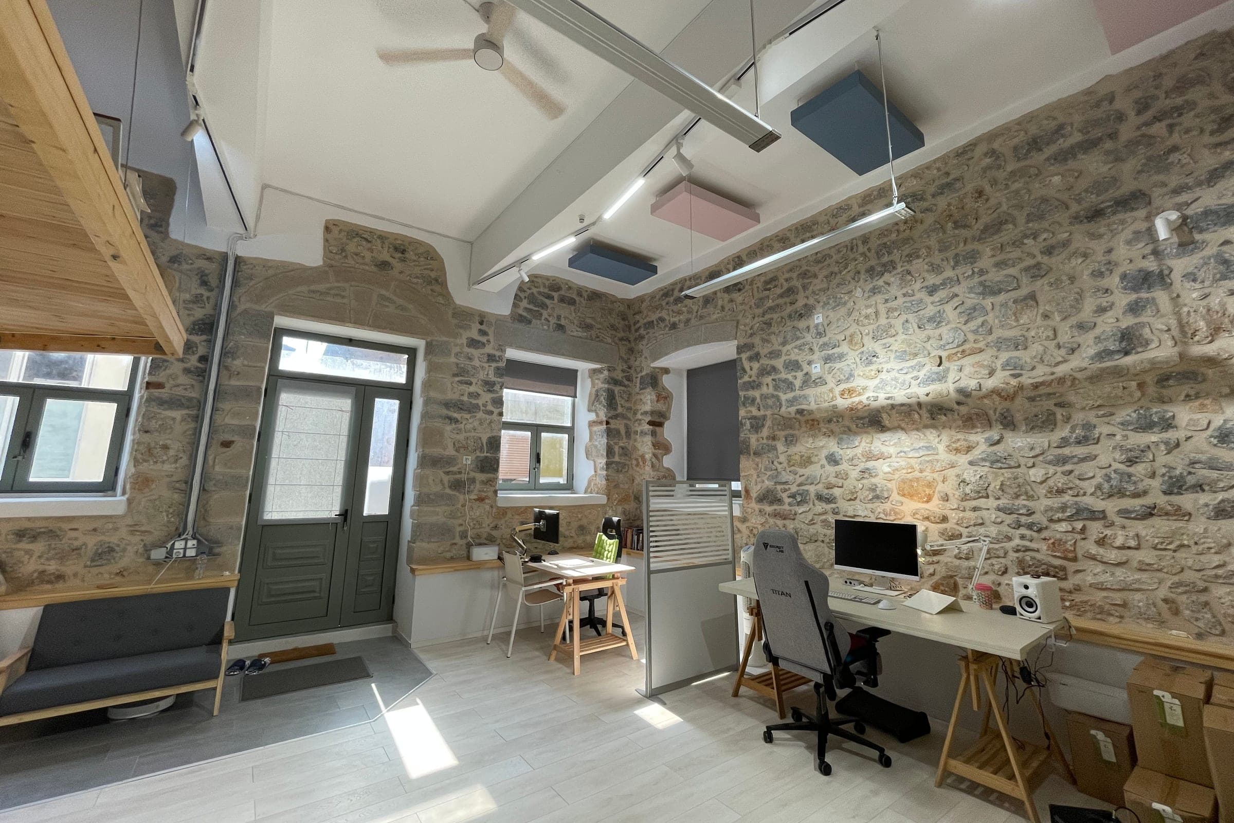 two desks with screens and office chairs near the front door and windows